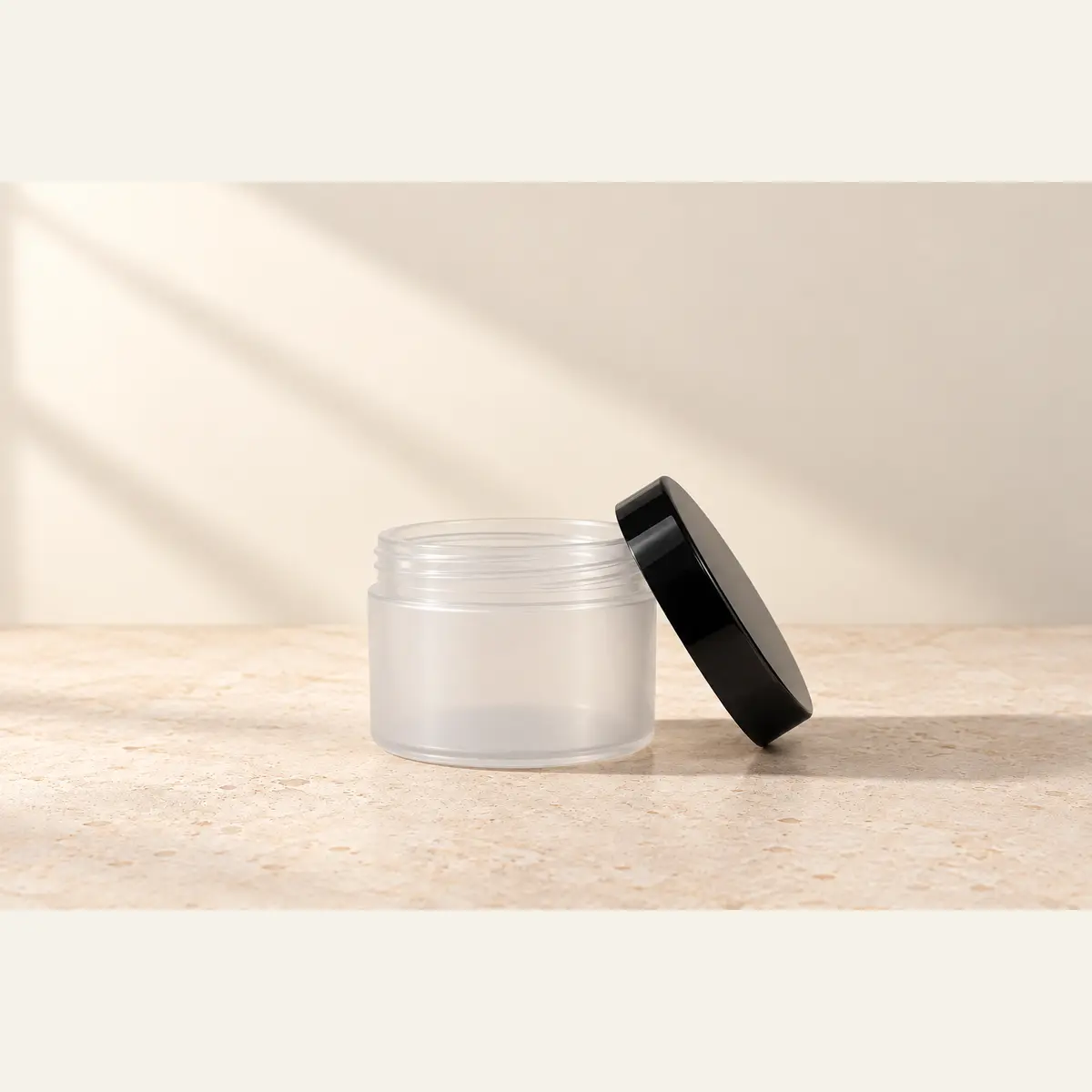 Natural 125 g Cosmetic Jar · Black Lid photographed on a warm neutral studio background